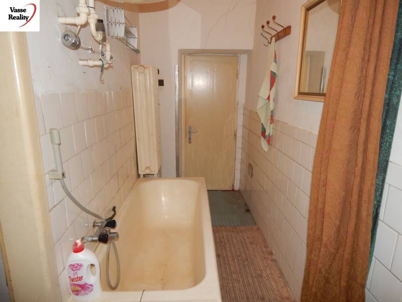 Ein Badezimmer in einem Einfamilienhaus mit einer älteren Badewanne und Fliesen an den Wänden.