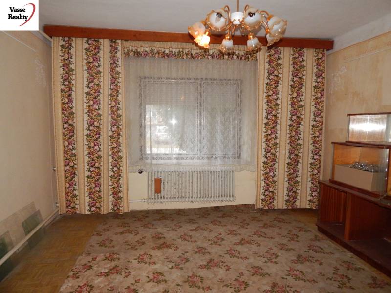 Ein Zimmer in einem Einfamilienhaus mit blumengemusterten Tapeten und einem zentralen Kronleuchter.