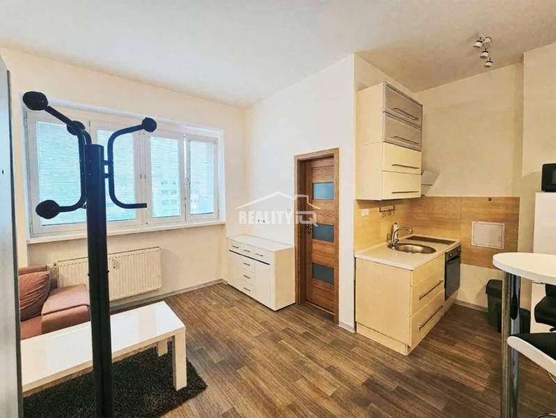 Ein Studio-Apartment mit Küchenzeile, Holzboden und Sitzbereich bietet einen gemütlichen Raum.