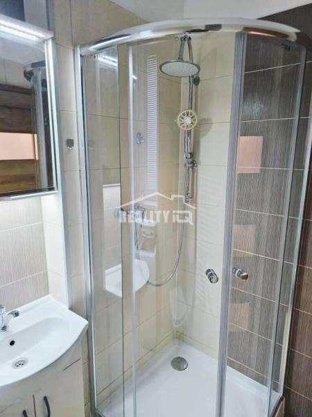 Badezimmer mit verglaster Duschkabine und hellen Fliesen in einem Studio.