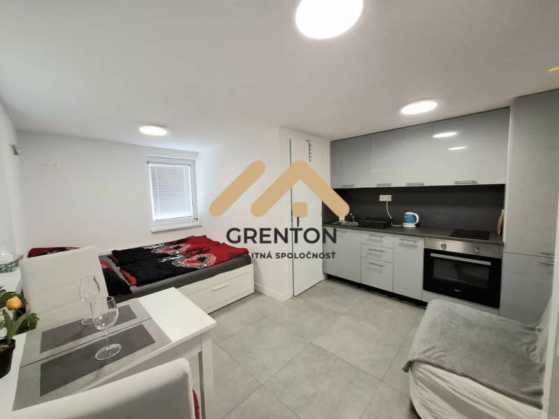 Küchenecke und Bett in einer Hütte mit grauer Verkleidung und Ausstattung.