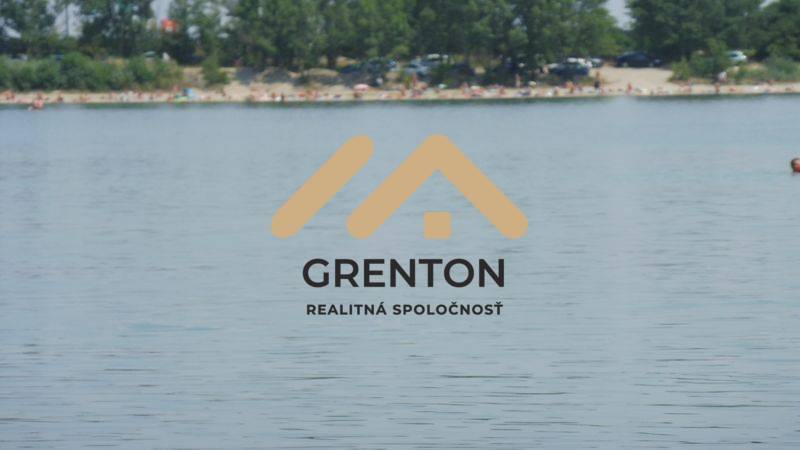 Das Logo des Immobilienunternehmens Grenton mit Blick auf eine Wasserfläche an der Küste.