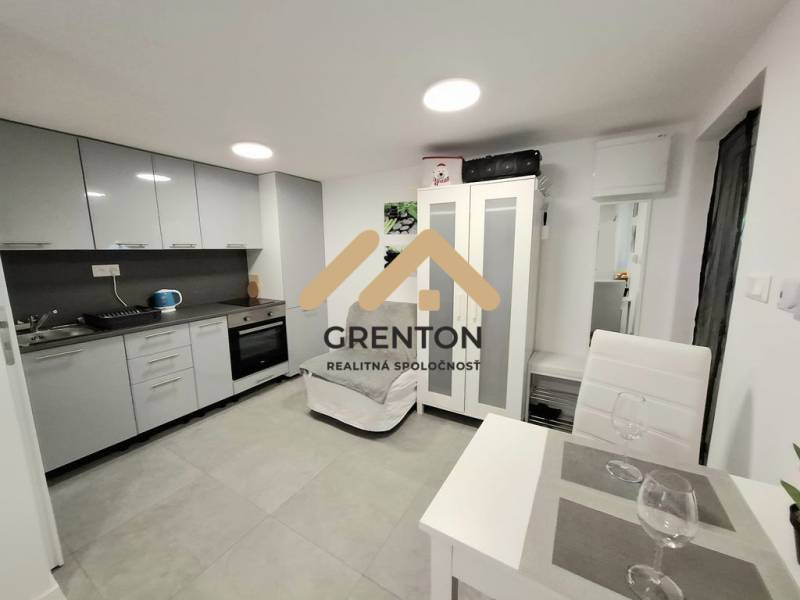 Eine Küche in einer Hütte, mit einem Esstisch und grauen Küchenschränken.