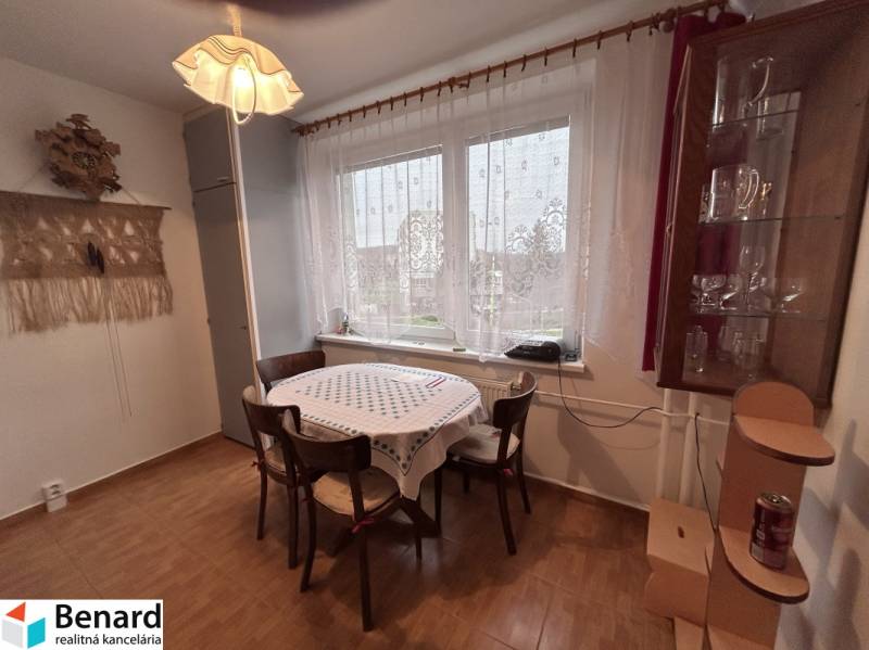 Essbereich in einer 2-Zimmer-Wohnung mit Holzboden, Tisch, Stühlen, Vorhängen.