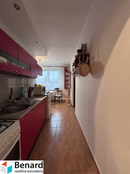 Küche in einer 2-Zimmer-Wohnung mit Holzboden und Essbereich im Hintergrund.