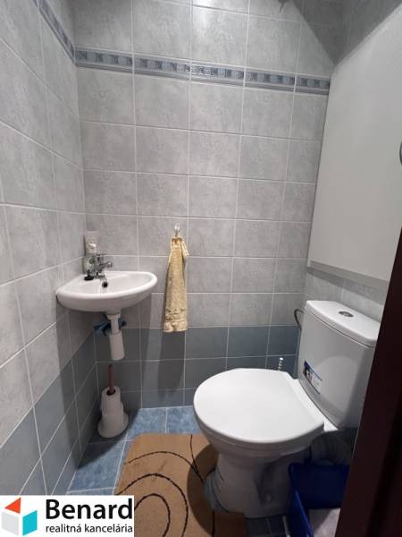 Badezimmer in einer 2-Zimmer-Wohnung mit Toilette und Waschbecken, umgeben von hellen Fliesen.