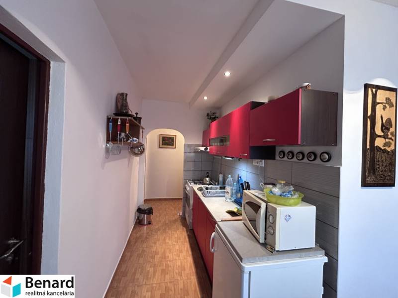 Küche mit roten Schränken und Holzboden in einer 2-Zimmer-Wohnung.