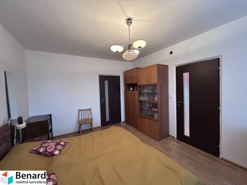 Schlafzimmer in einer 2-Zimmer-Wohnung mit Bett, Schrank und Boden in Holzoptik.