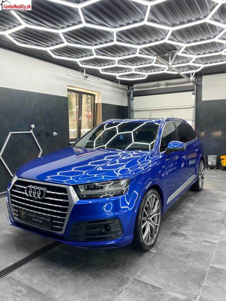 Audi SUV in Geschäftsräumen mit gefliestem Boden und geometrischen Deckenleuchten.