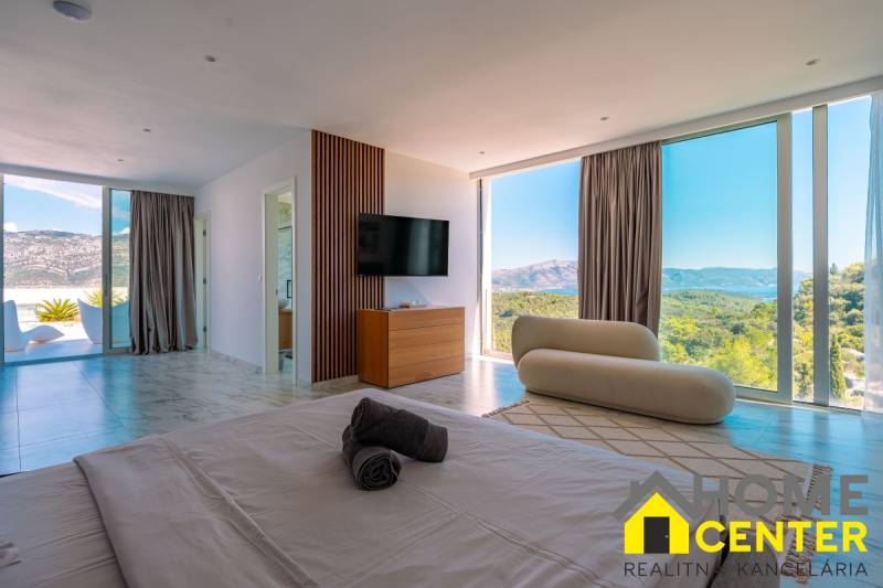 Helles Schlafzimmer in der Villa mit Blick durch große Fenster, Holzboden.