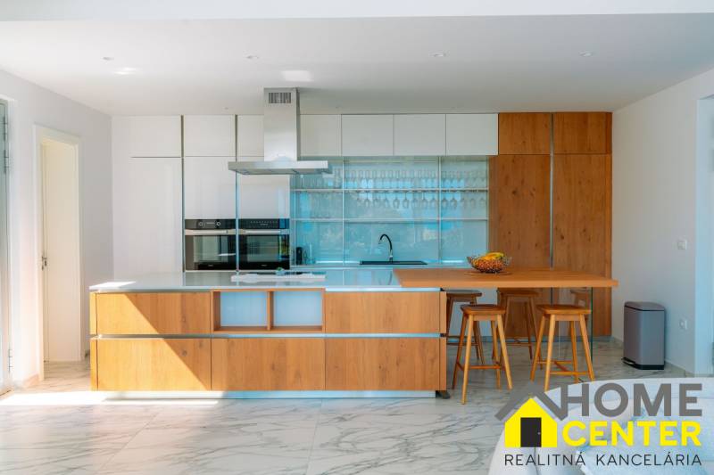 Küche in der Villa mit Holzboden, Kücheninsel und Barhockern.