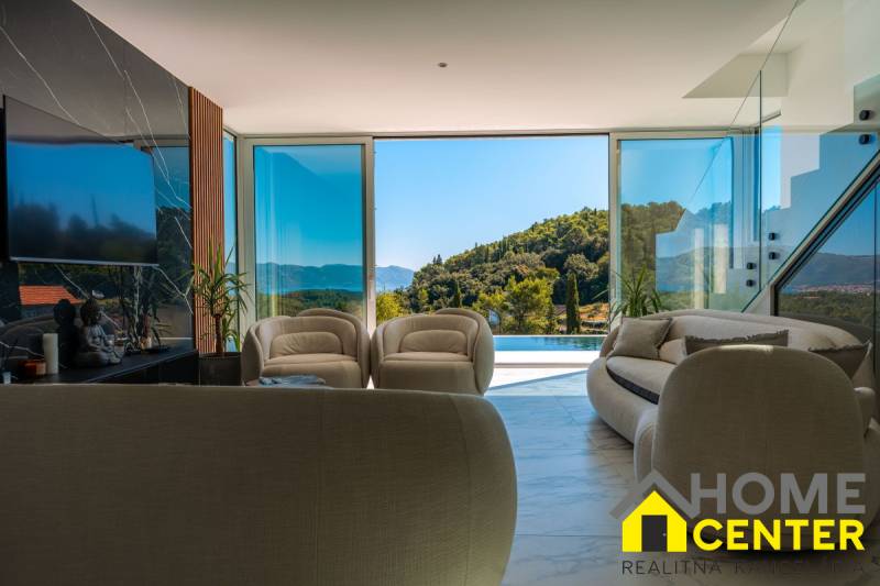 Das Innere der Villa mit großen Fenstern, Blick auf das Grün und den Pool.