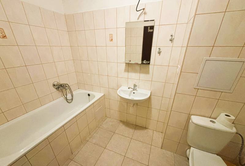 Badezimmer einer Zweizimmerwohnung mit klassischer Badewanne und Fliesen in neutralen Tönen.