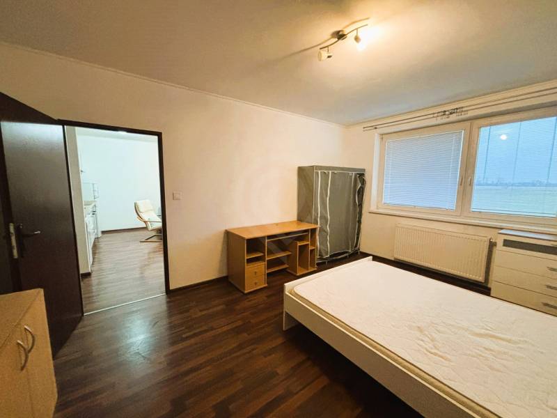 Schlafzimmer in einer 2-Zimmer-Wohnung mit Holzboden und einfachem Möbel.