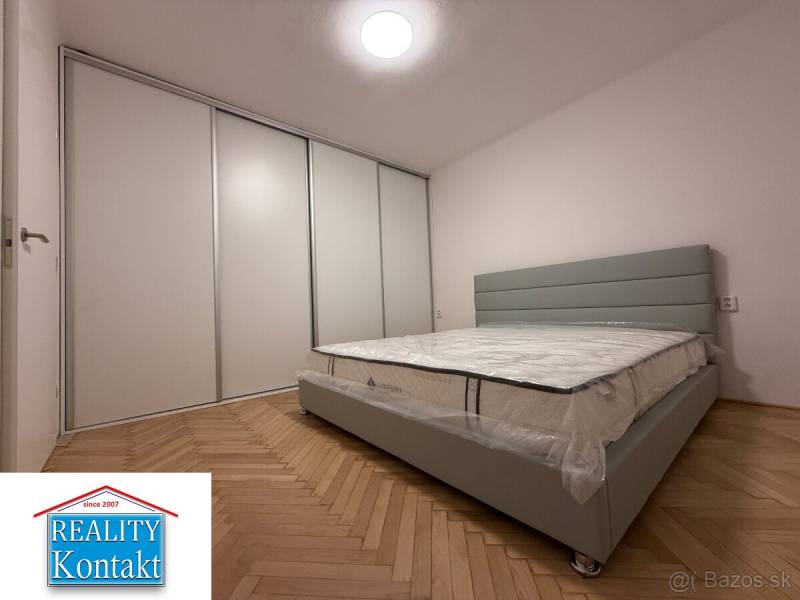 Schlafzimmer in einer 2-Zimmer-Wohnung mit Holzboden und einem großen Einbauschrank.