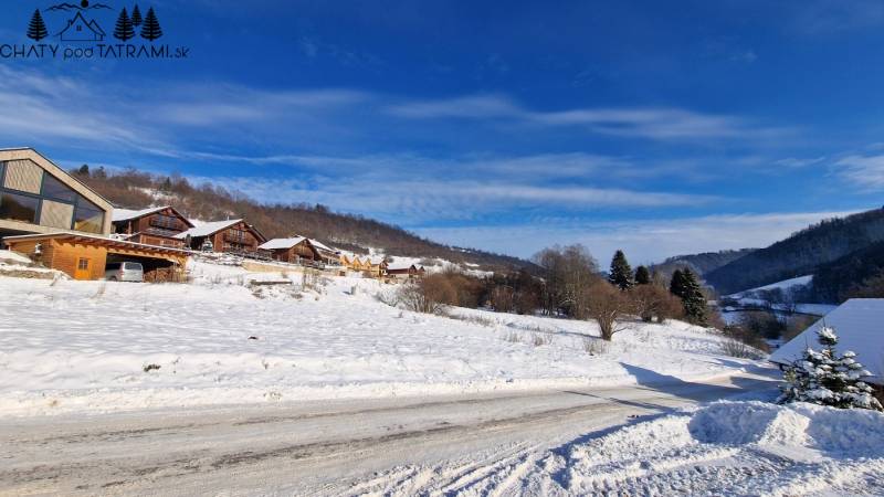 Verschneite Landschaft mit Holzhütten auf den Erholungsgrundstücken bei der Straße Fongrub in Mýto pod Ďumbierom.