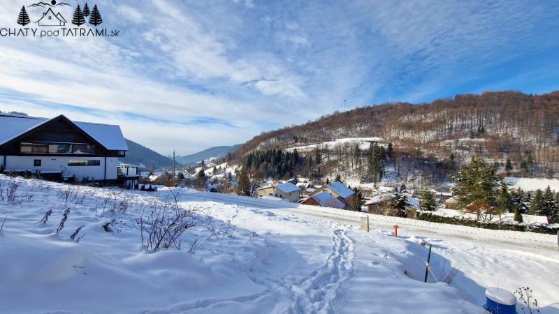 Schneebedeckte Wohnbaugrundstücke in Mýto pod Ďumbierom bieten ein Winterpanorama der Berge.
