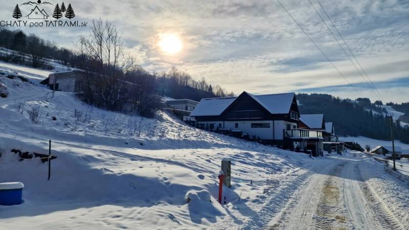 Eine verschneite Straße in Mýto pod Ďumbierom mit Blick auf die Häuser und die umliegende Landschaft.