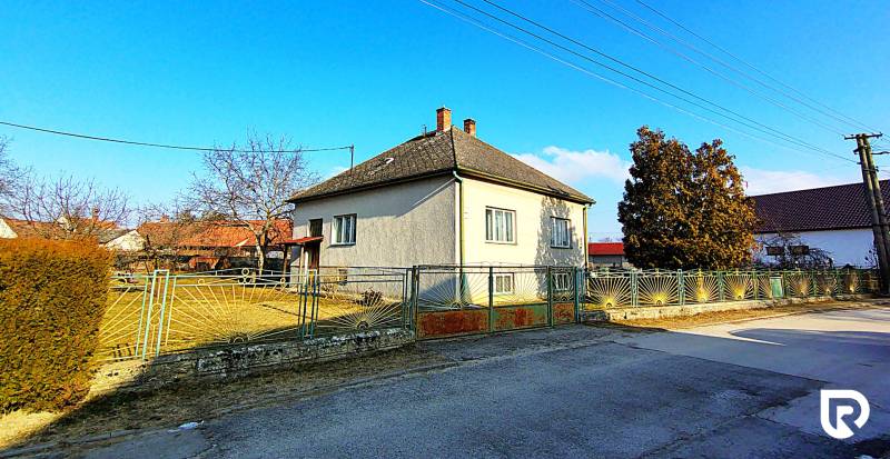 Ein Einfamilienhaus in der Sadova-Straße in Borský Mikuláš mit einem eingezäunten Garten und blauem Himmel.
