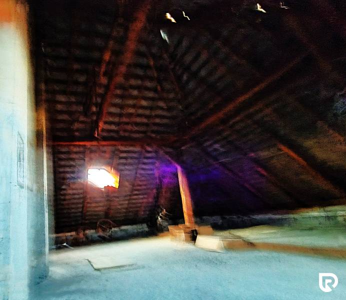 Dachboden in einem Einfamilienhaus mit Holzbalken und Fenster.