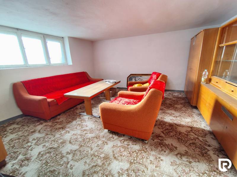 Wohnzimmer in einem Einfamilienhaus mit einem orangefarbenen Sofa, einem Holztisch und einer Vitrine.
