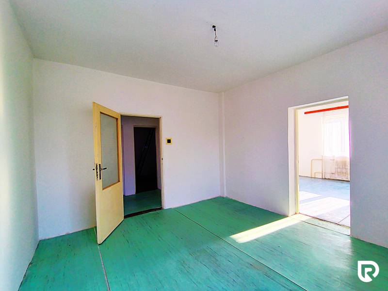 Innenraum eines Einfamilienhauses mit offenen Türen, weißen Wänden und grünem Boden.