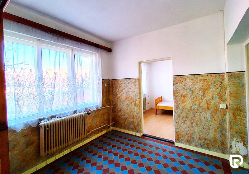 Innenraum eines Einfamilienhauses mit Fliesen, Heizkörper und Fenster mit Gardine.