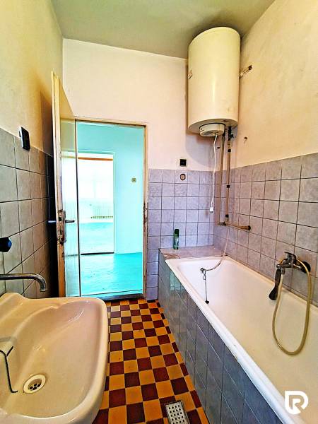 Ein Badezimmer in einem Einfamilienhaus mit einer Badewanne, einem Waschbecken und einem Schachbrettmuster-Fliesenboden.