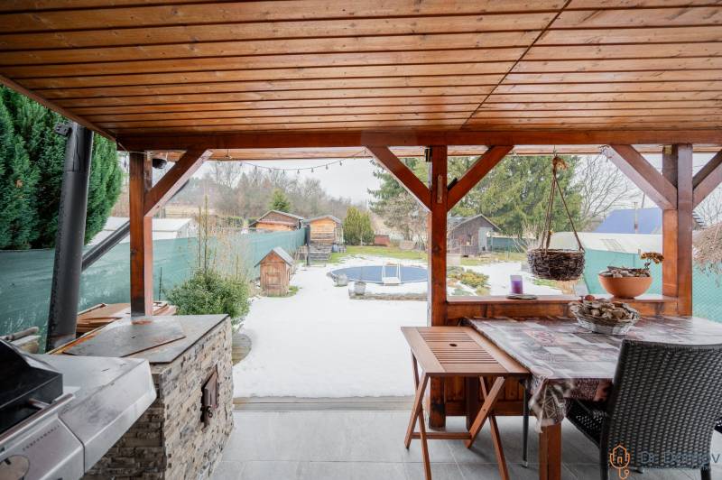 Ein Holzunterstand bei einer Hütte in Handlová, mit Blick auf den verschneiten Garten und die Zäune.