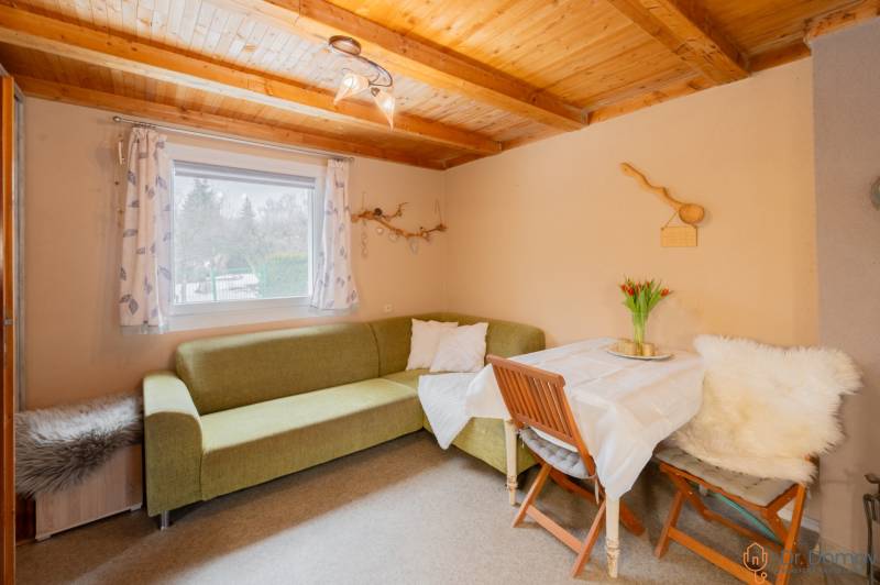 Das Innere der Hütte mit einer Eckcouch, einem Tisch und einer Holzdecke.