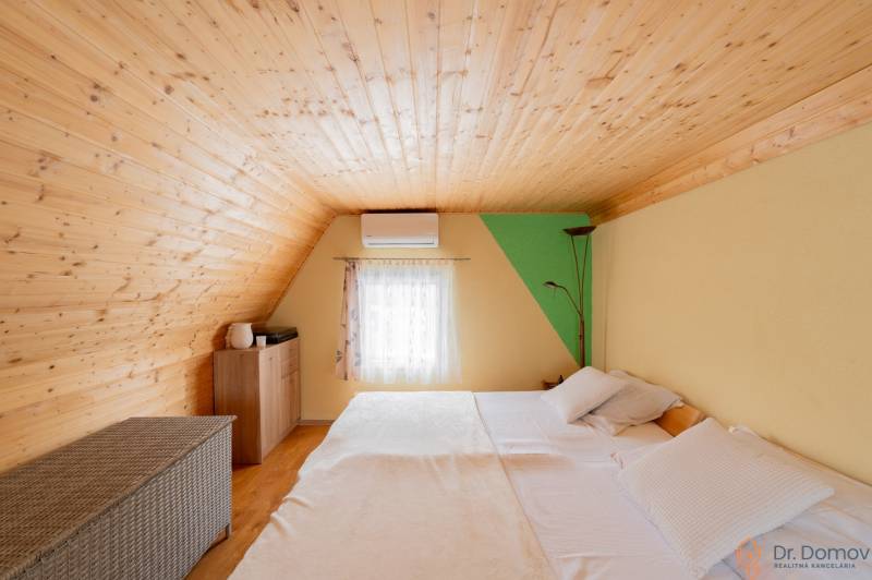 Ein Dachzimmer in einer Hütte mit einer Holzdecke und einem Bett, Boden mit Holzdekor.