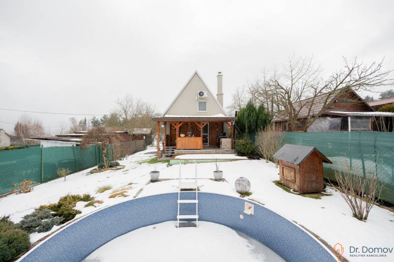 Ein verschneiter Garten mit einer Hütte in Handlová und einem leeren Pool im Vordergrund.