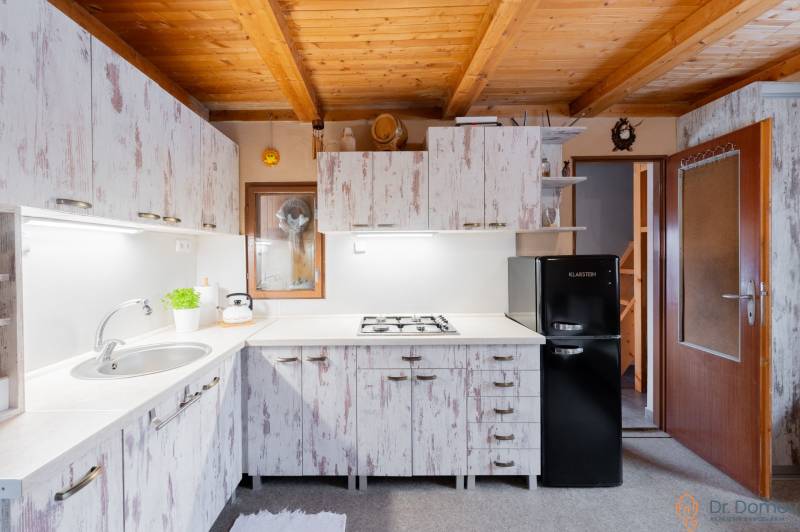 Eine Küche in einer Hütte mit einer Holzdecke und Vintage-Schränken, gemütliche Ausstattung.