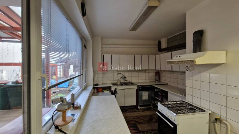 Küche in einem Einfamilienhaus mit Geräten, Fliesen und einem Fenster mit Blick auf die Terrasse.