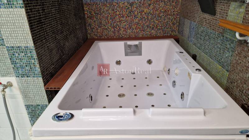 Im Badezimmer eines Einfamilienhauses befindet sich eine große Whirlpool-Badewanne, die mit bunten Mosaikfliesen verziert ist.