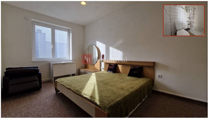 Schlafzimmer mit Doppelbett, grüner Decke, Nachttisch und Spiegel in einem Einfamilienhaus.