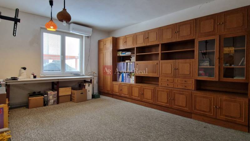 Das Einfamilienhaus hat ein Arbeitszimmer mit einer Holzregalwand, einem großen Tisch und einem Teppichboden.