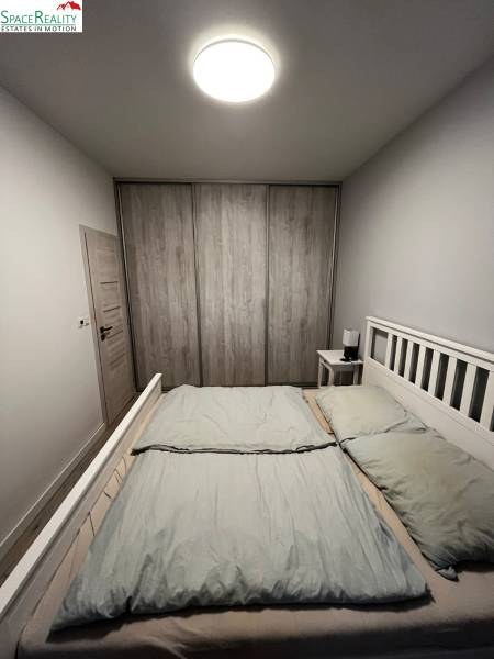 Helles Schlafzimmer in einer 2-Zimmer-Wohnung mit geräumigem Bett und Schrank in Holzoptik.