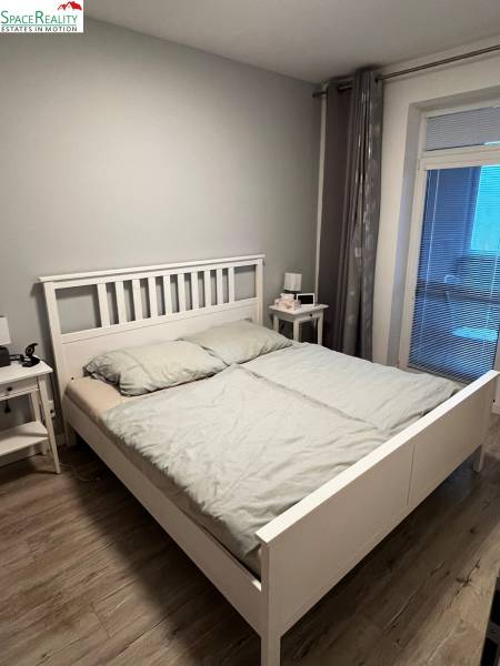 Schlafzimmer mit Holzboden und einfachem Bett in einer Zweizimmerwohnung.