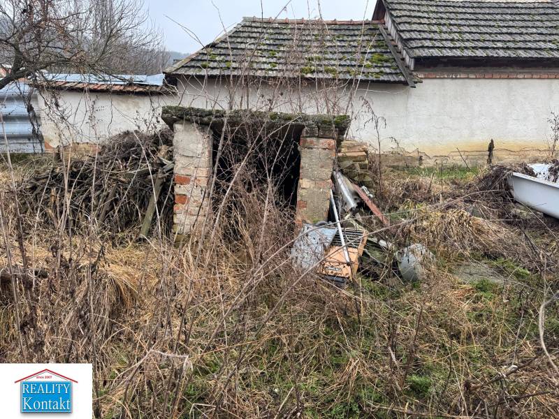 Ein verlassenes Gebäude auf einem Grundstück in Dubník mit ungepflegter Umgebung und alten Dächern.