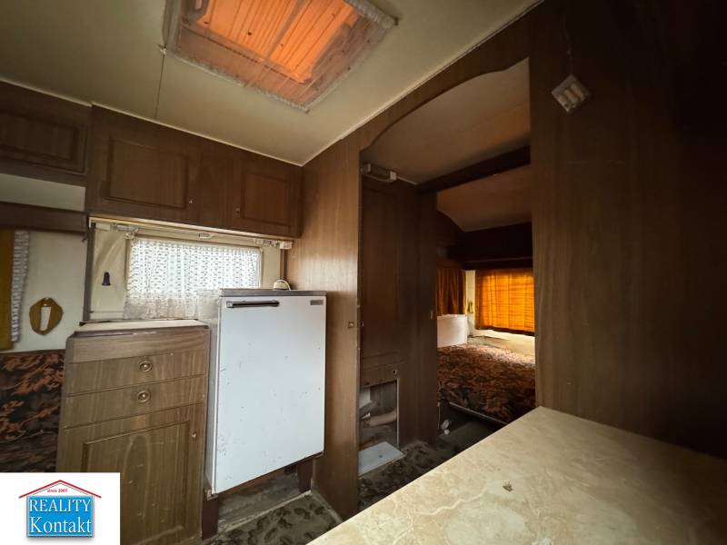 Innenraum mit Holzboden, Küchenzeile und Bett in einem Grundstück - Wohnen.