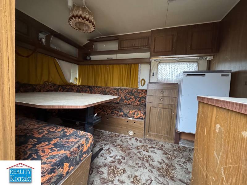 Innenraum eines Wohnbereichs mit Teppichboden, Sitzgarnitur und Tisch.