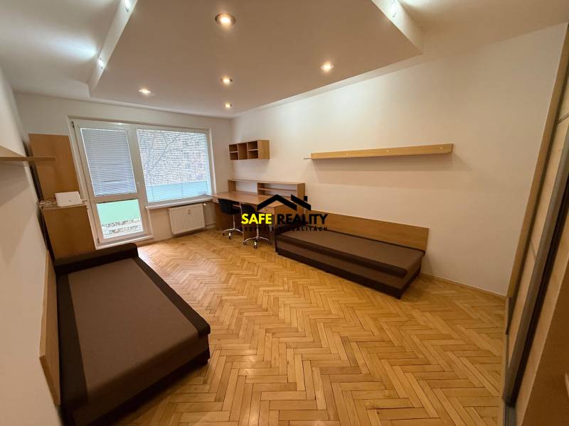 Wohnzimmer in einer 3-Zimmer-Wohnung mit Holzboden und Schreibtisch.