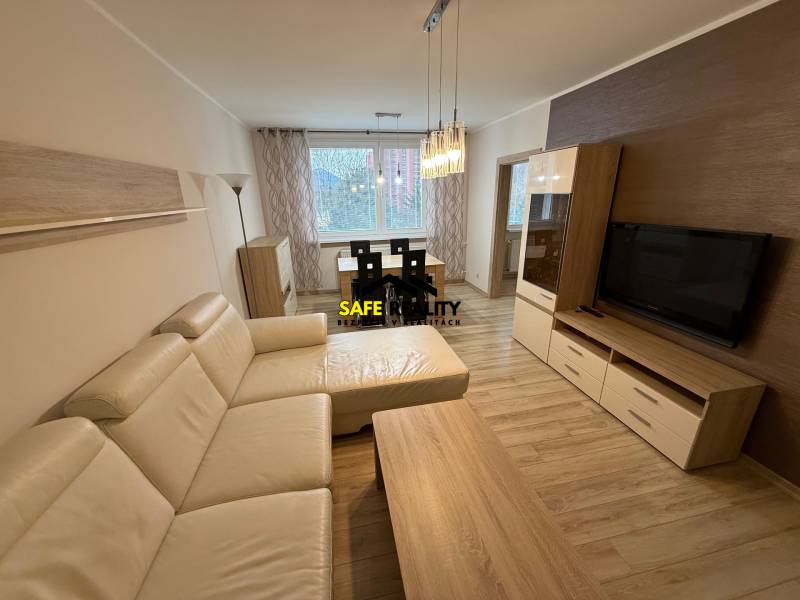 Wohnzimmer mit Holzboden, großem Sofa und Esstisch in einer 3-Zimmer-Wohnung.