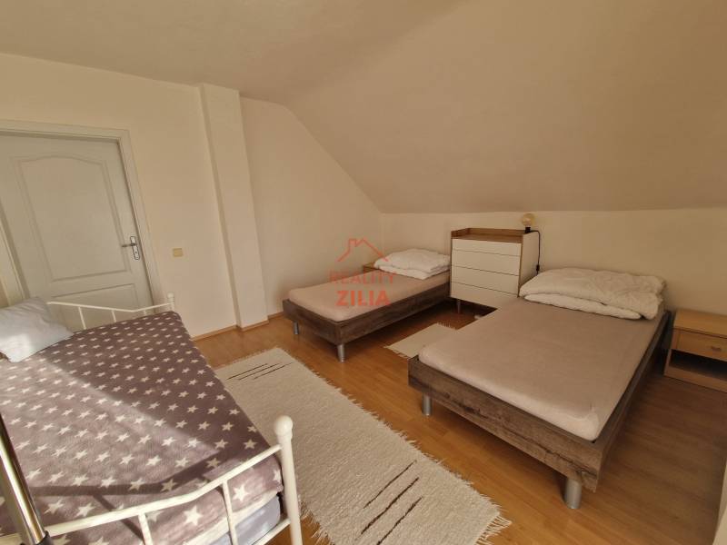 Schlafzimmer im Einfamilienhaus mit drei Betten und einem Boden in Holzoptik.