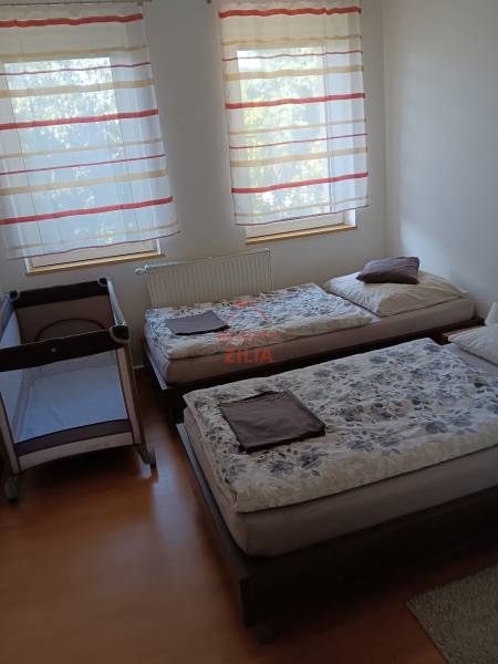 Ein Kinderbett und zwei Betten im Schlafzimmer mit einem Boden in Holzoptik.