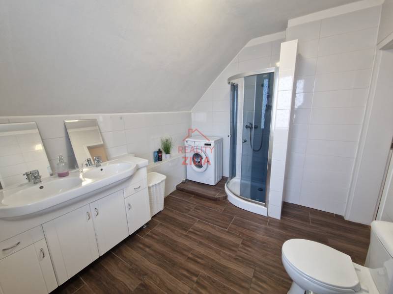 Badezimmer in einem Einfamilienhaus mit Waschbecken, Duschkabine und Boden mit Holzdekor.