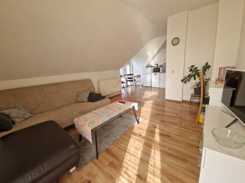 Wohnzimmer im Dachgeschoss eines Einfamilienhauses mit Sofa, Esstisch und Holzboden.