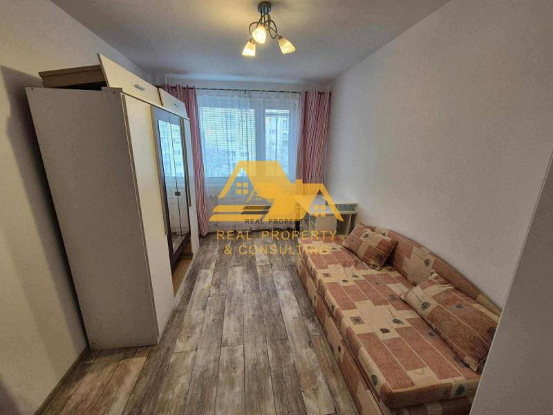 Ein Zimmer in einer 3-Zimmer-Wohnung mit einem Sofa, einem Schrank und einem Boden mit Holzdekor.