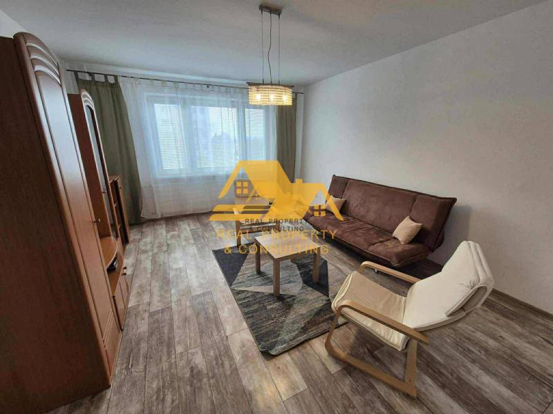 Wohnzimmer in einer 3-Zimmer-Wohnung mit Sofa, Sessel und Boden in Holzoptik.